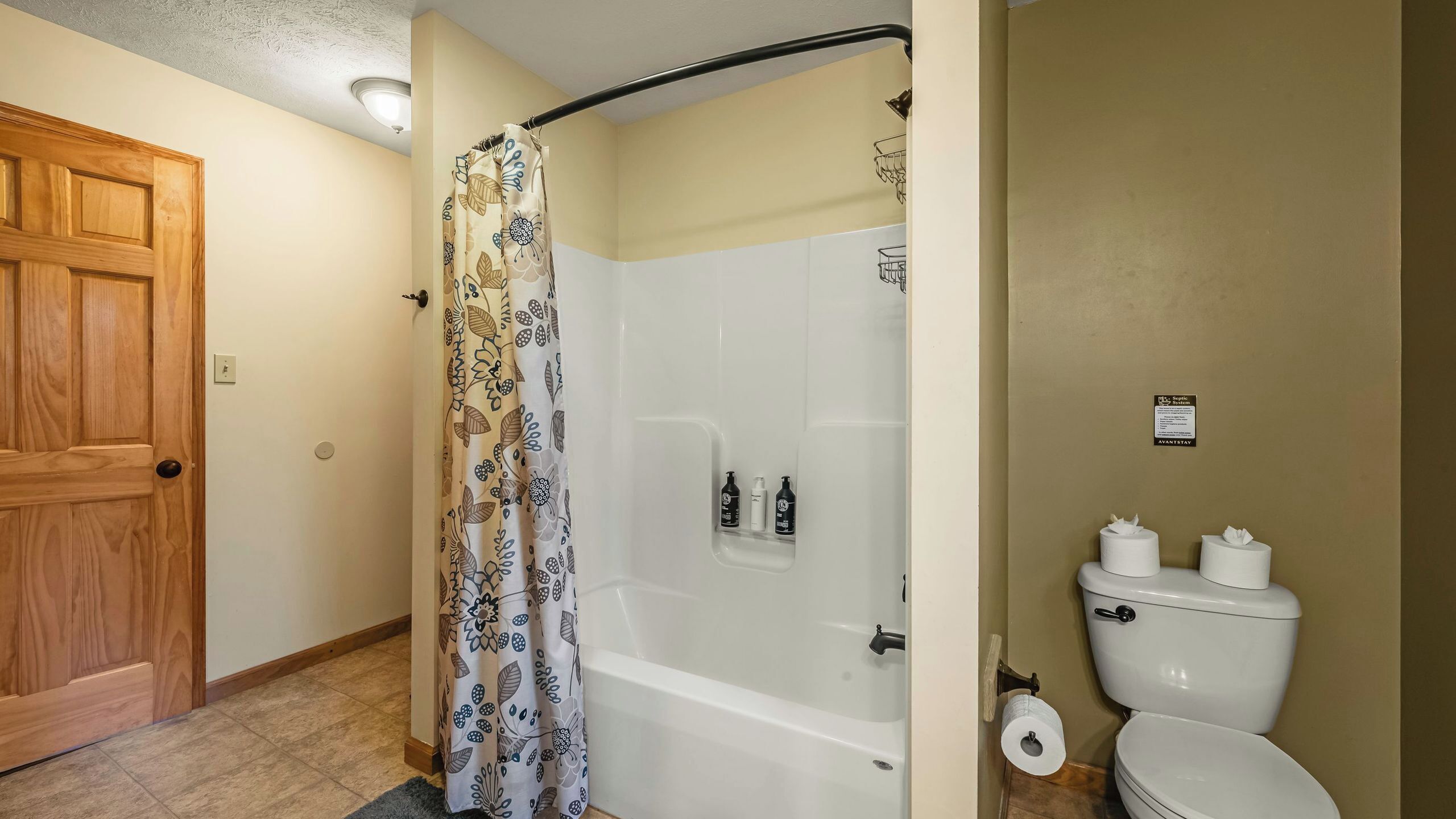 A bathroom with a shower, toilet, and a door.