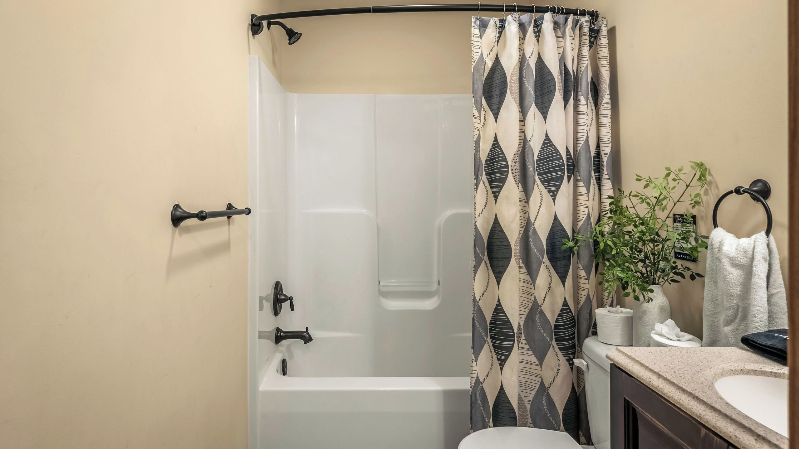 A bathroom with a shower, a toilet, a sink, a towel rack, and a potted plant.