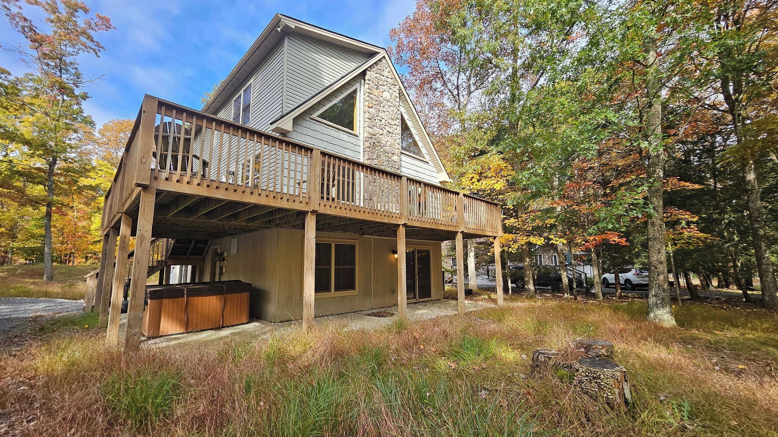 A two-story cabin with a wooden deck and a stone facade.