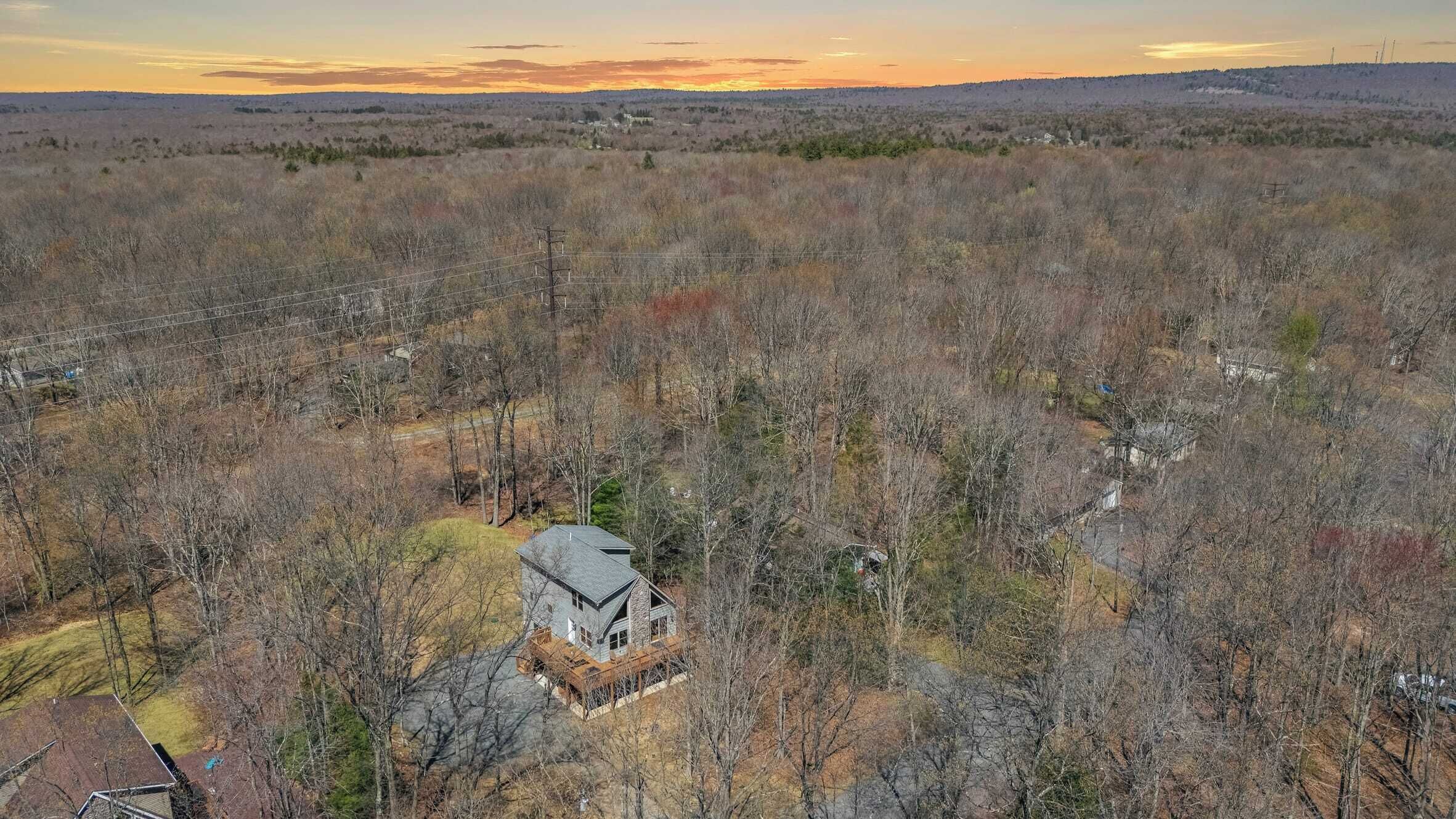 Uma casa grande e térrea, cercada por uma área arborizada, com vista clara do céu.