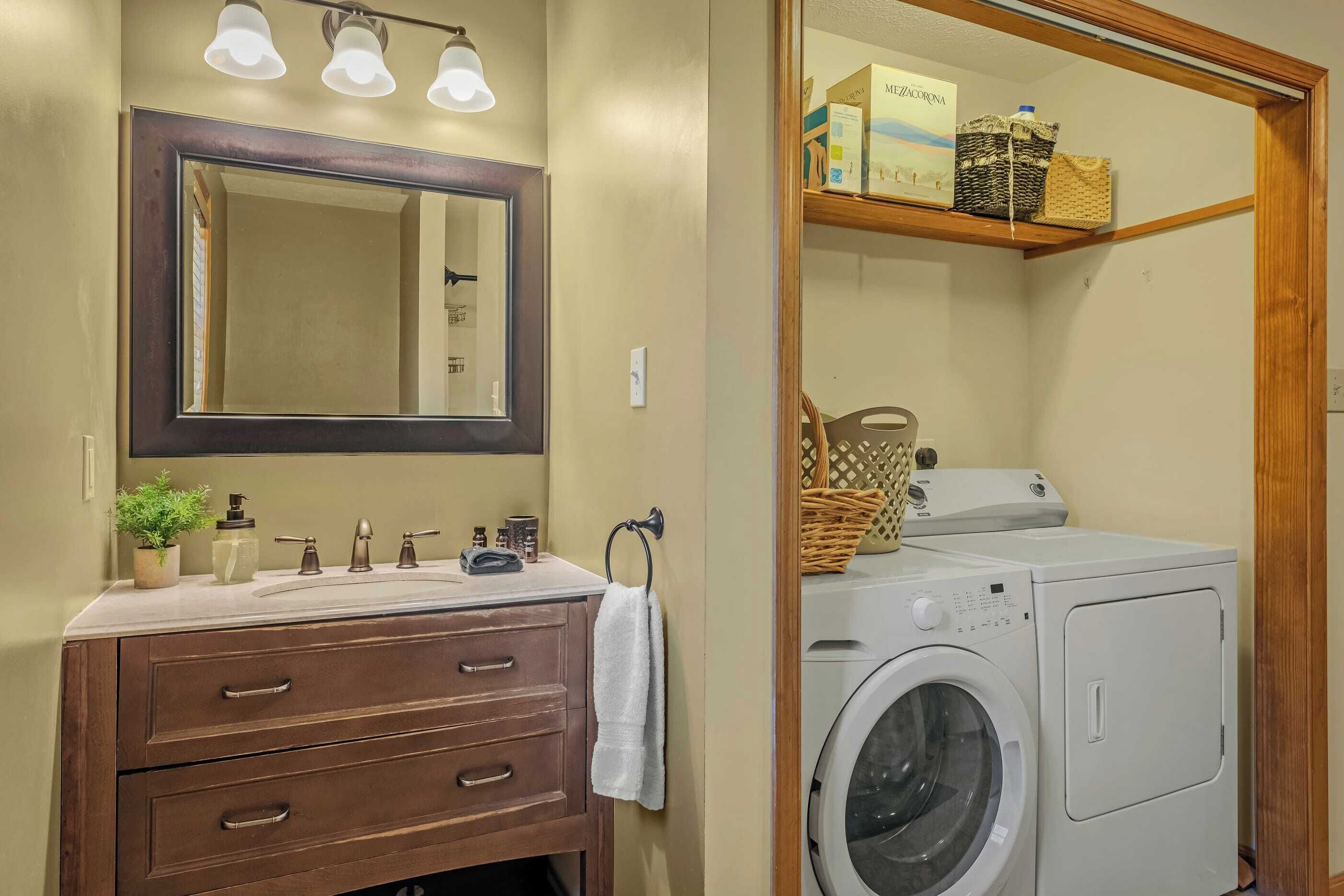 Casa de banho com lavatório, espelho e máquina de lavar roupa.