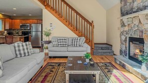 Ein geräumiges Wohnzimmer mit grauem Sofa, einem Couchtisch und einem Kamin.