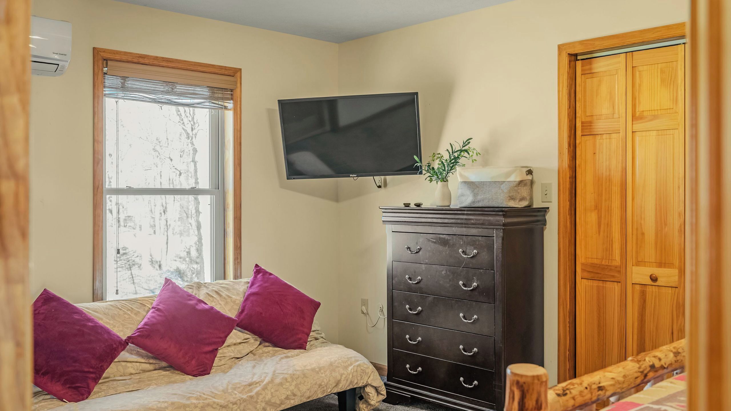 A bedroom with a bed, a dresser, a television, and a window.
