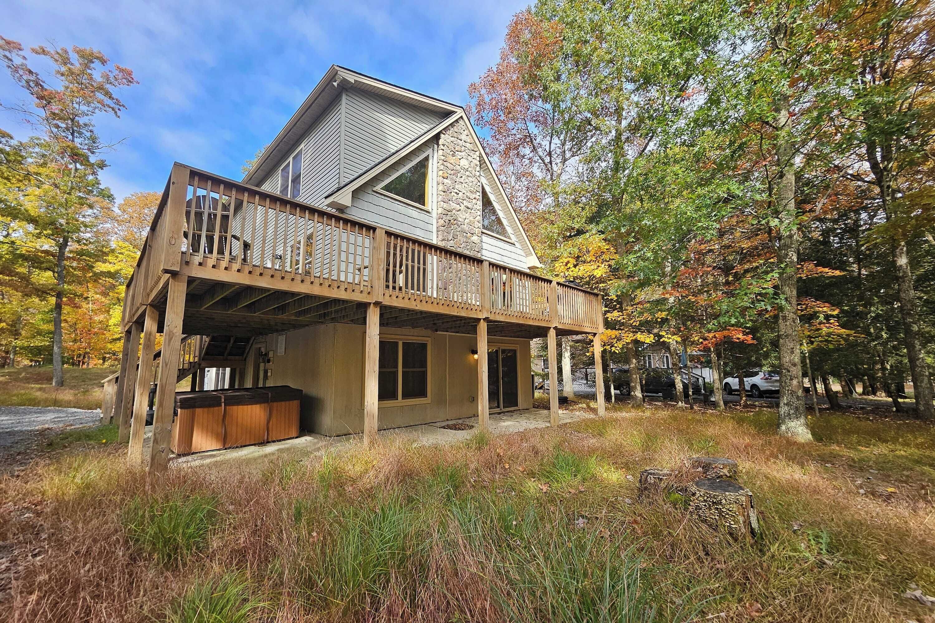 A two-story house with a wooden deck and a stone chimney.
