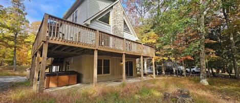 A two-story house with a wooden deck and a stone chimney.