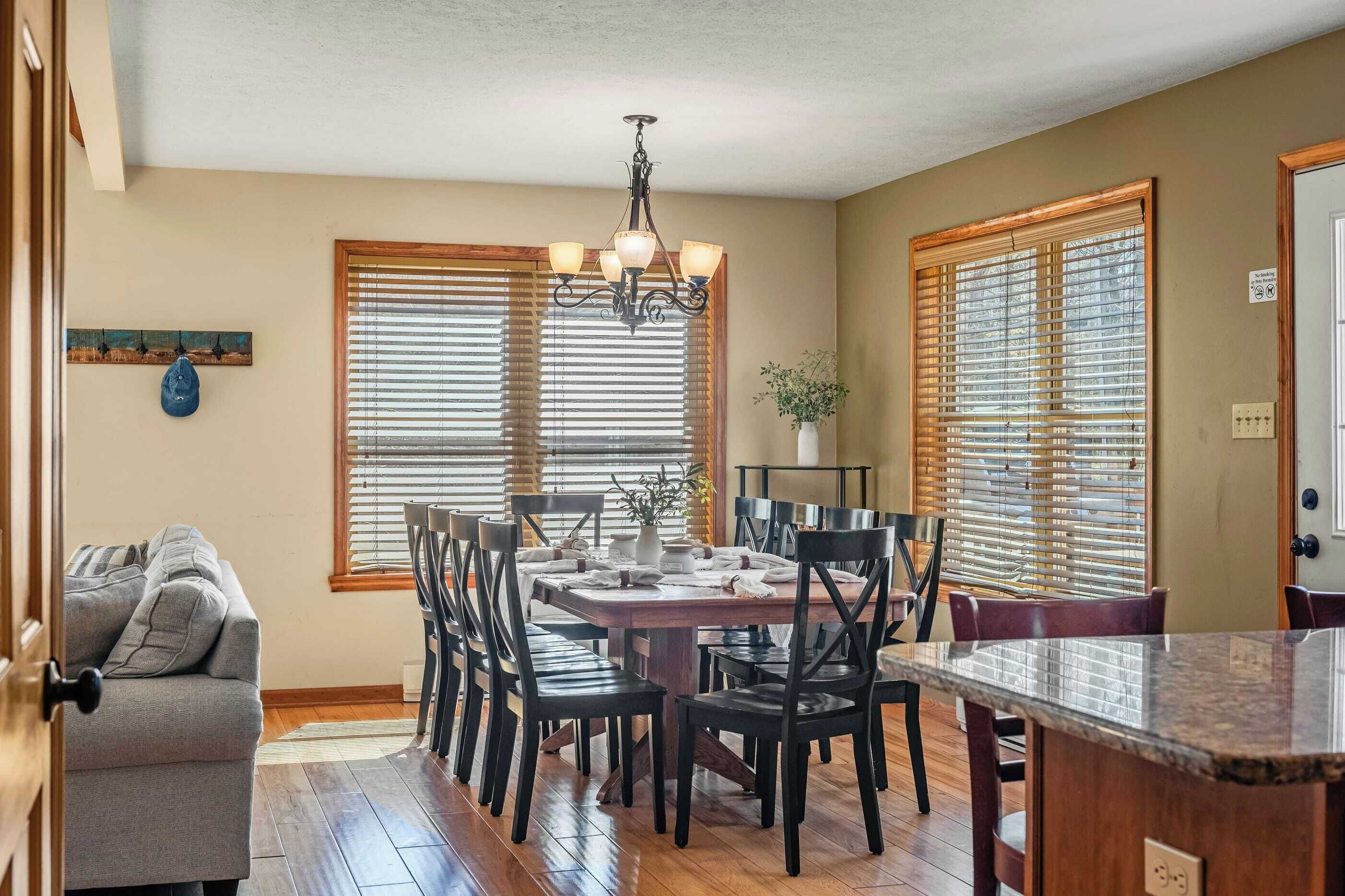 A dining area with a wooden table, black chairs, and a chandelier.