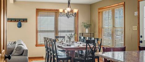 A dining area with a wooden table, black chairs, and a chandelier.