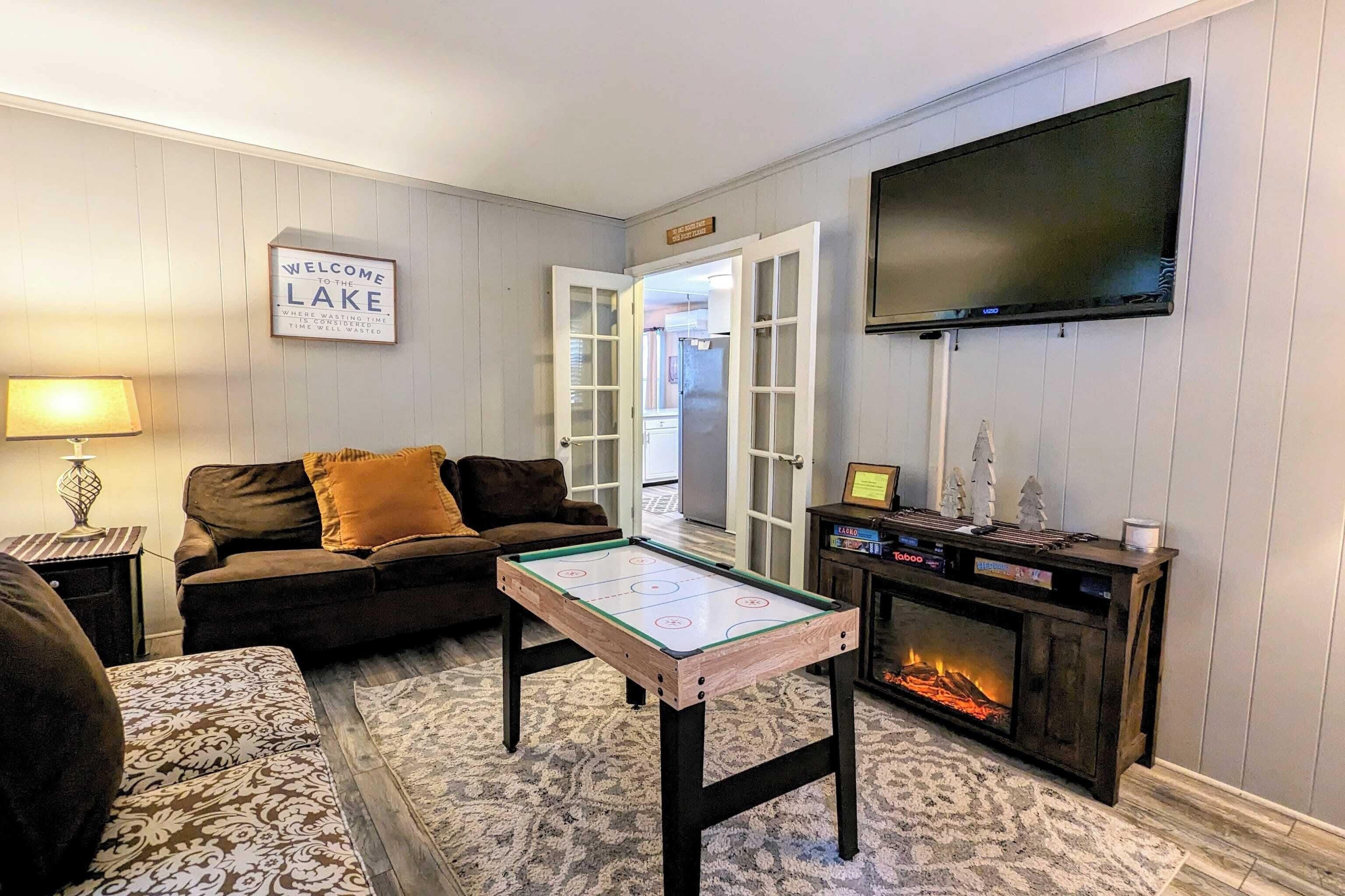 A living room with a pool table, a fireplace, a television, and a couch.