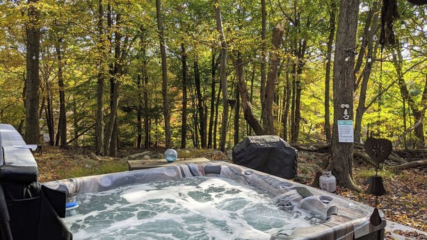 A hot tub in a forested area with a sign indicating rules.