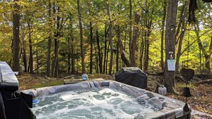 Un jacuzzi en un área boscosa con un cartel que indica las normas.