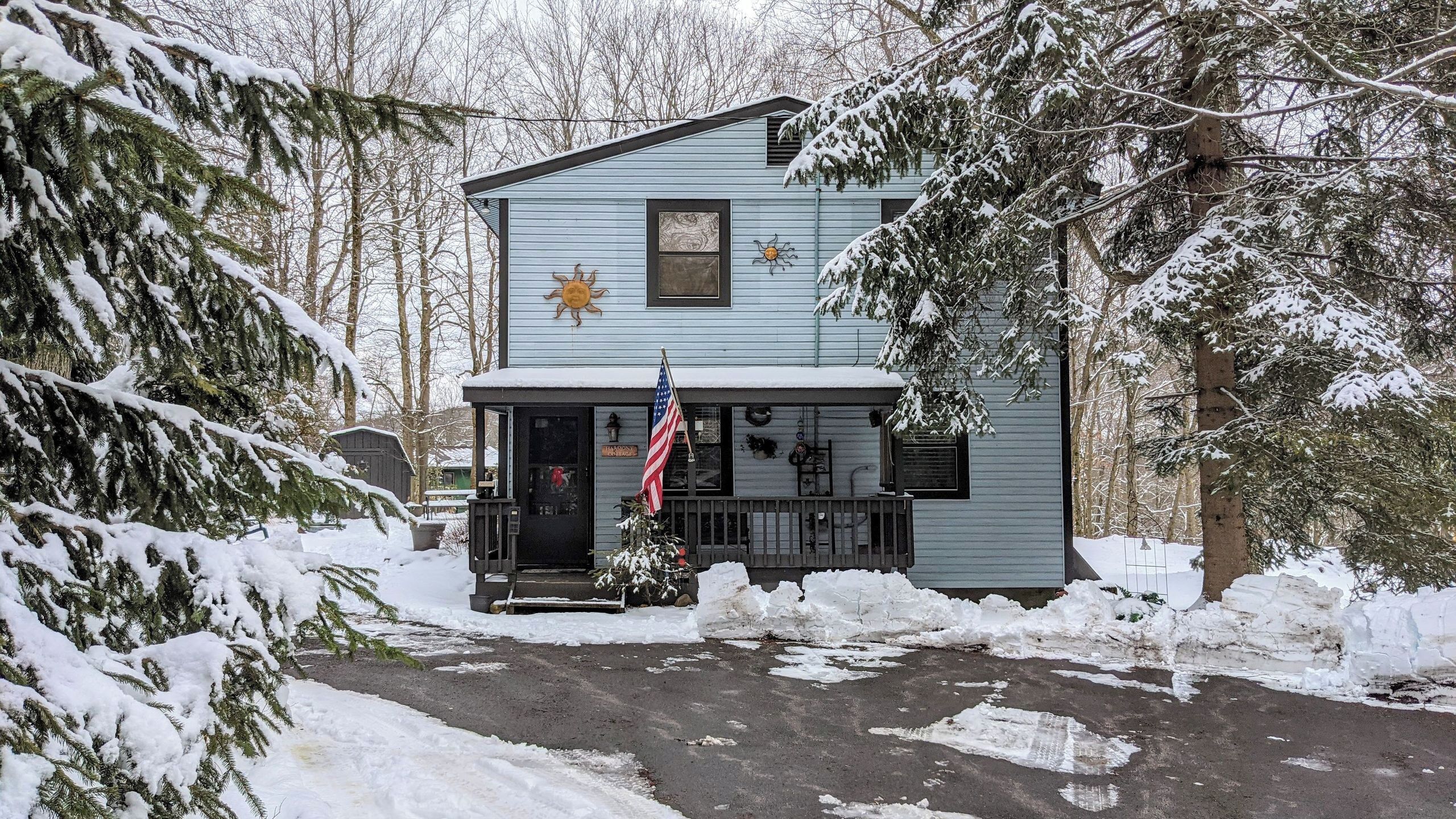 Un edificio a due piani con un portico, una bandiera americana e dintorni innevati.