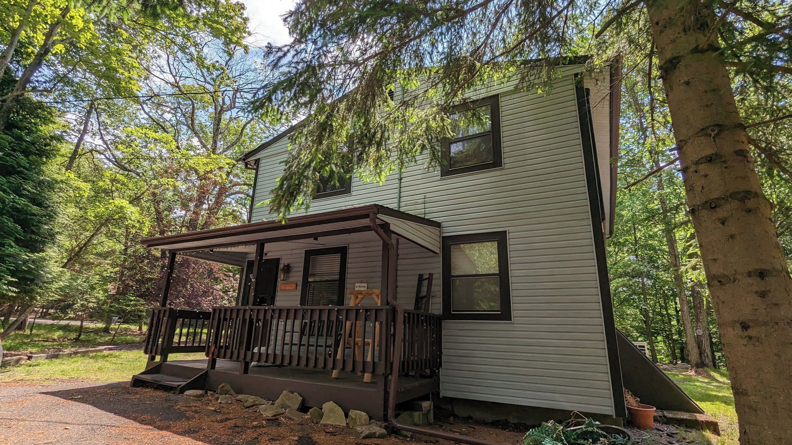 A two-story cabin with a porch, surrounded by trees.
