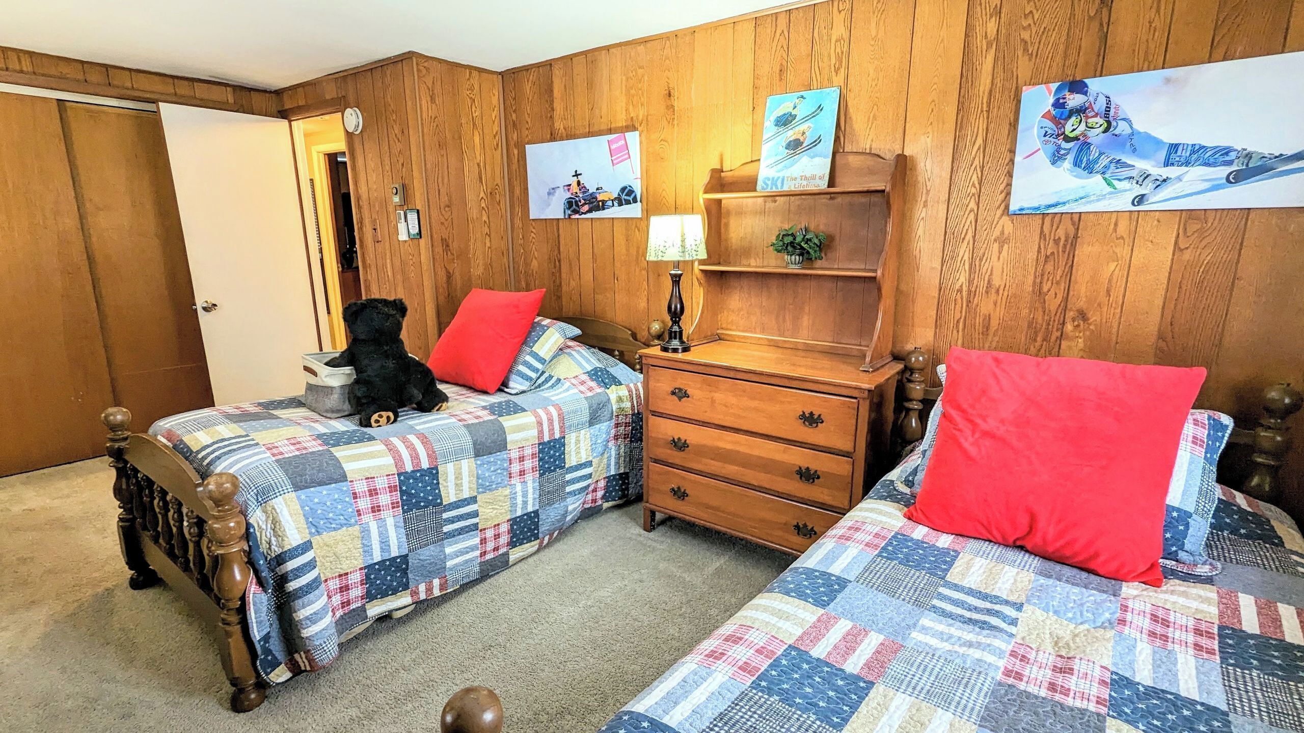 Ein Zimmer mit zwei Holzbett, einem Schminktisch, einer Uhr und Wandbildern.