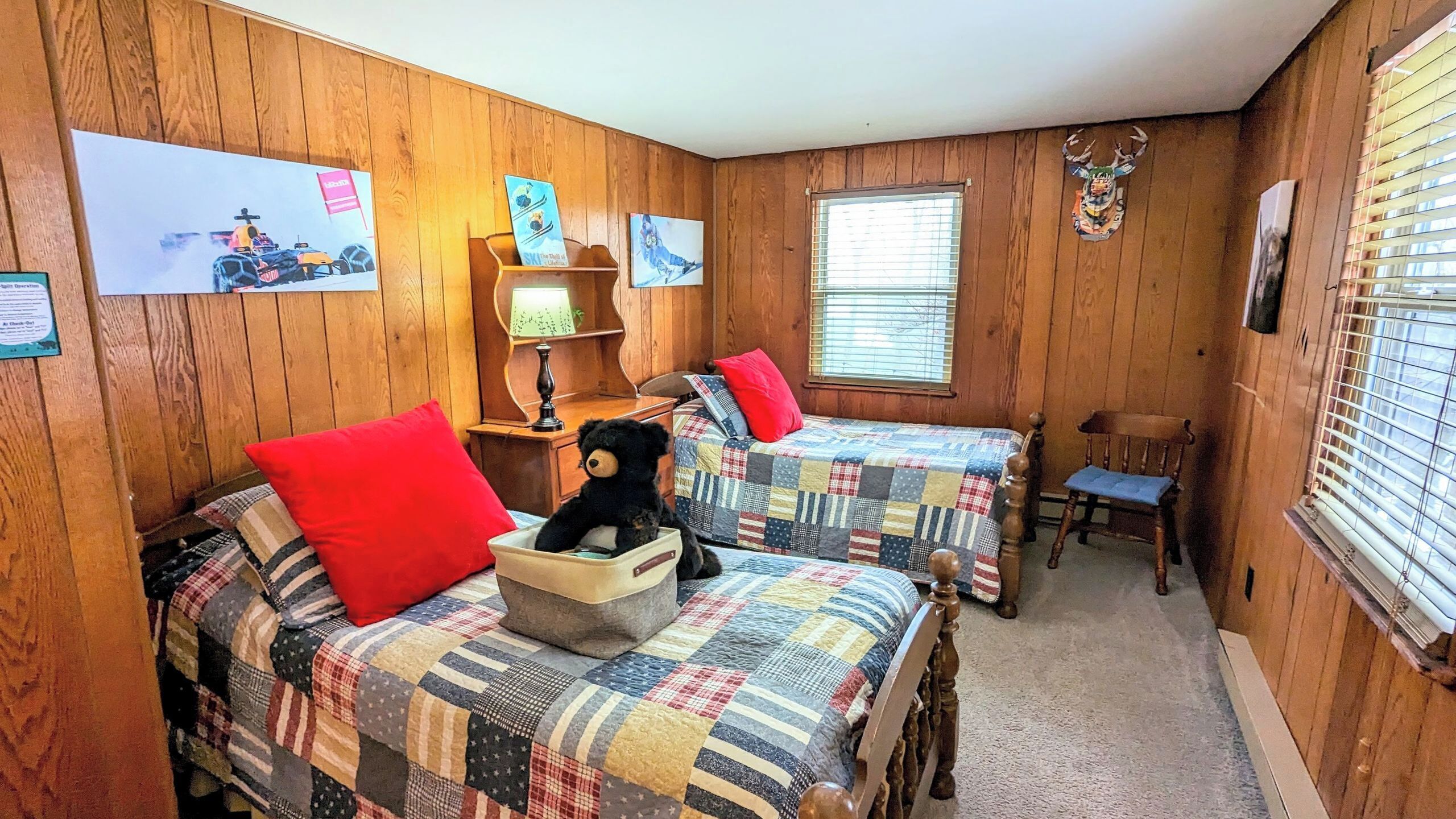 A room with two beds, a chair, a lamp, and a wall with pictures.