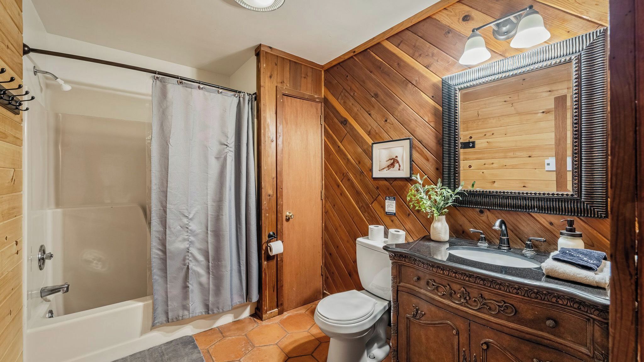 A wooden-paneled bathroom with a shower, toilet, sink, and vanity.