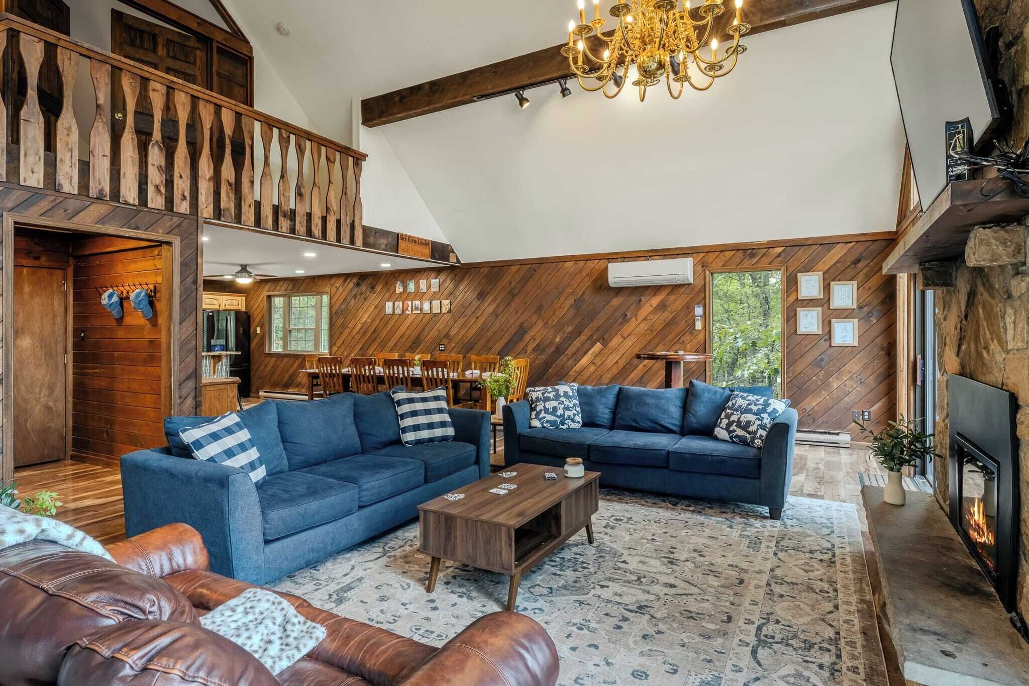 Un salon spacieux avec deux canapés bleus, une table basse en bois et une cheminée.
