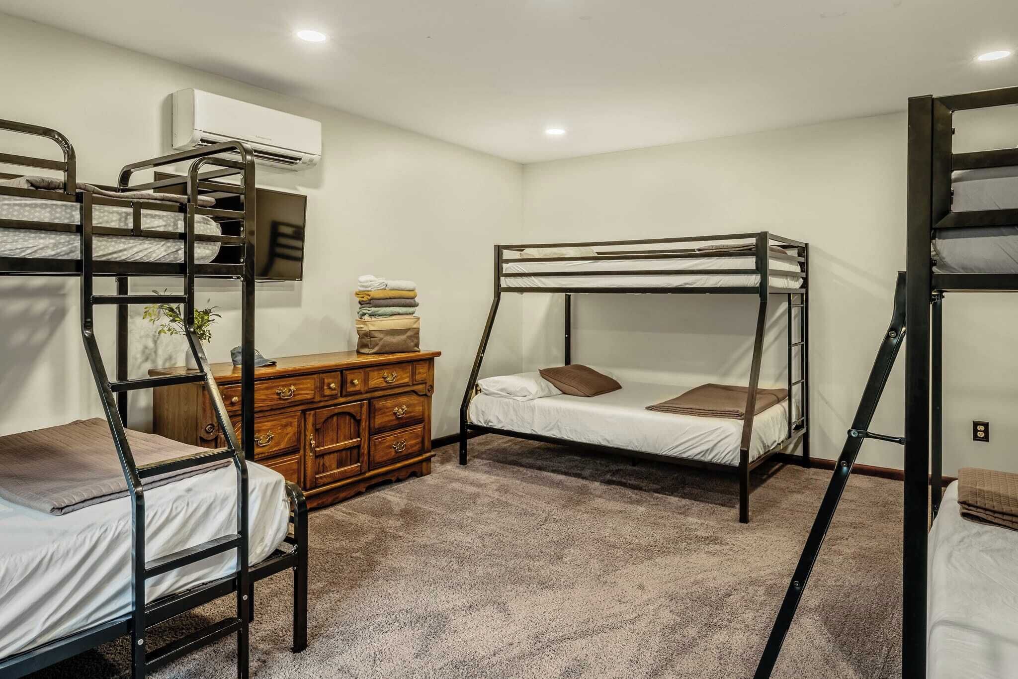 Ein Zimmer mit Etagenbetten, einem Holzschrank und einer Klimaanlage.