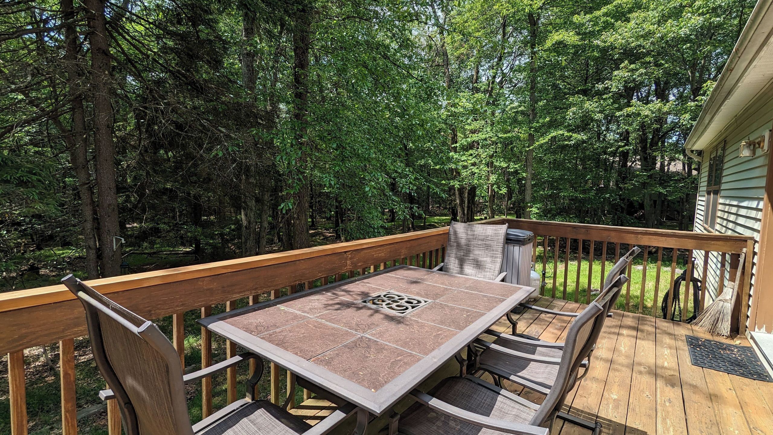 A wooden deck with a table and chairs, surrounded by trees.
