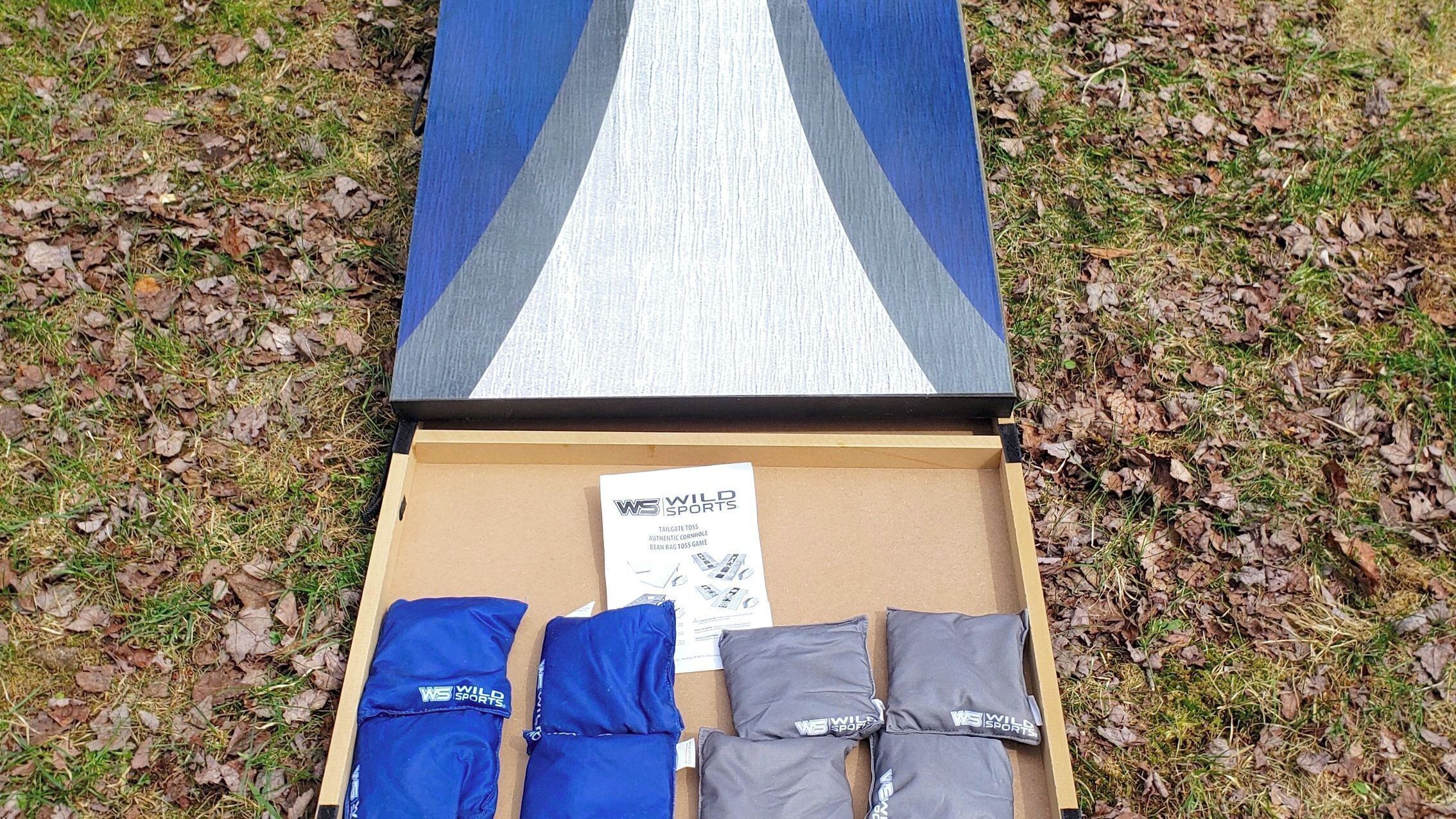 A cardboard box with a pair of blue and gray sports pants and a white and blue bag.