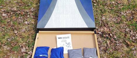 A cardboard box with a pair of blue and gray sports pants and a white and blue bag.