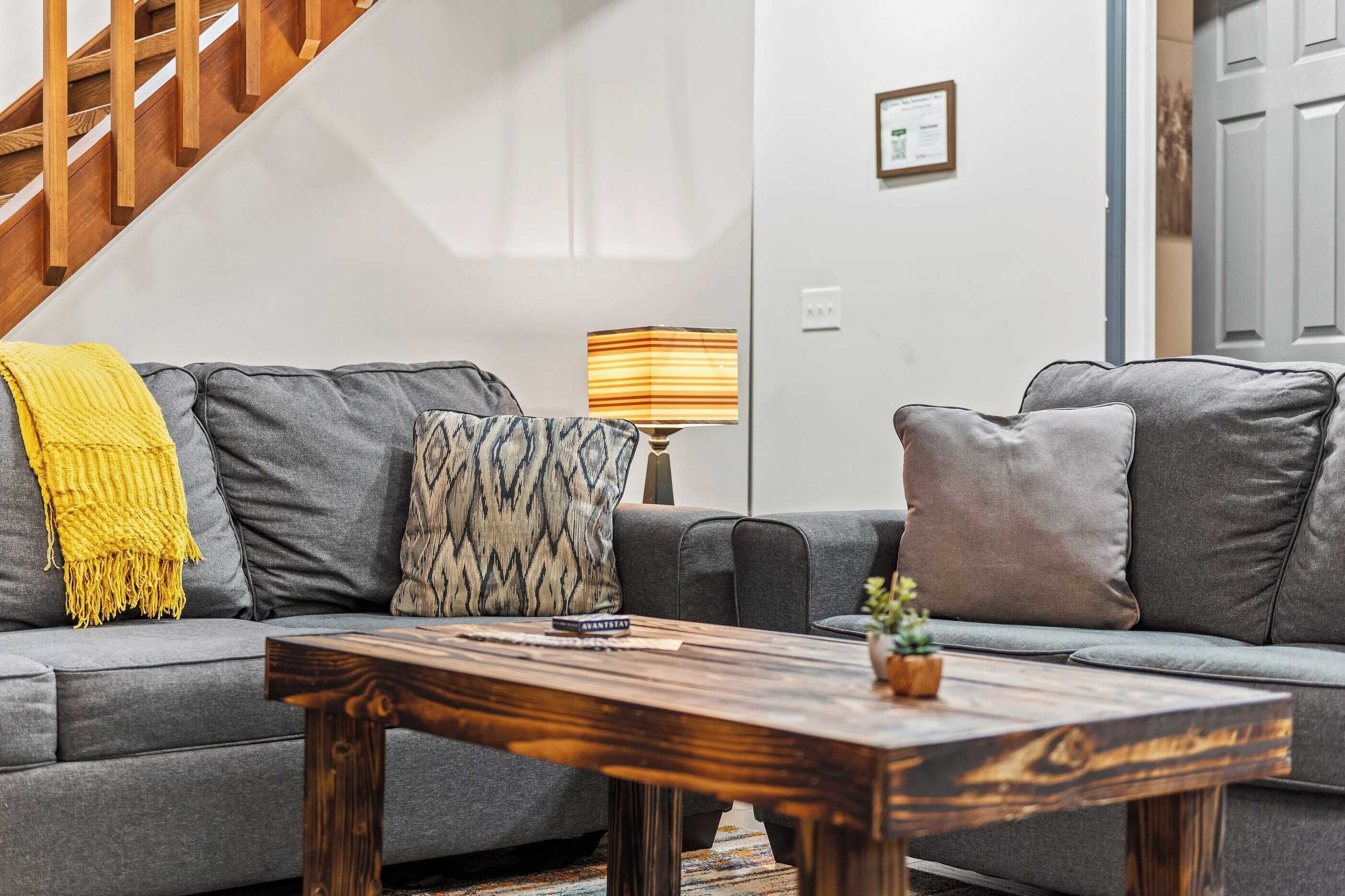 A modern living room with a grey sofa, a wooden coffee table, and a lamp.