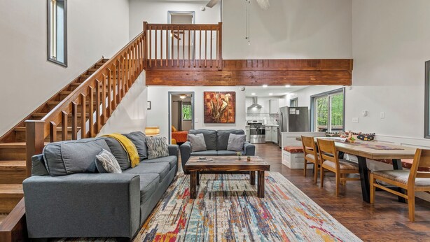A spacious living area with a staircase, a dining table, and a kitchen in the background. - The Tranquil Trails by Avantstay Lake Access, Deck, Fireplace (Albrightsville)