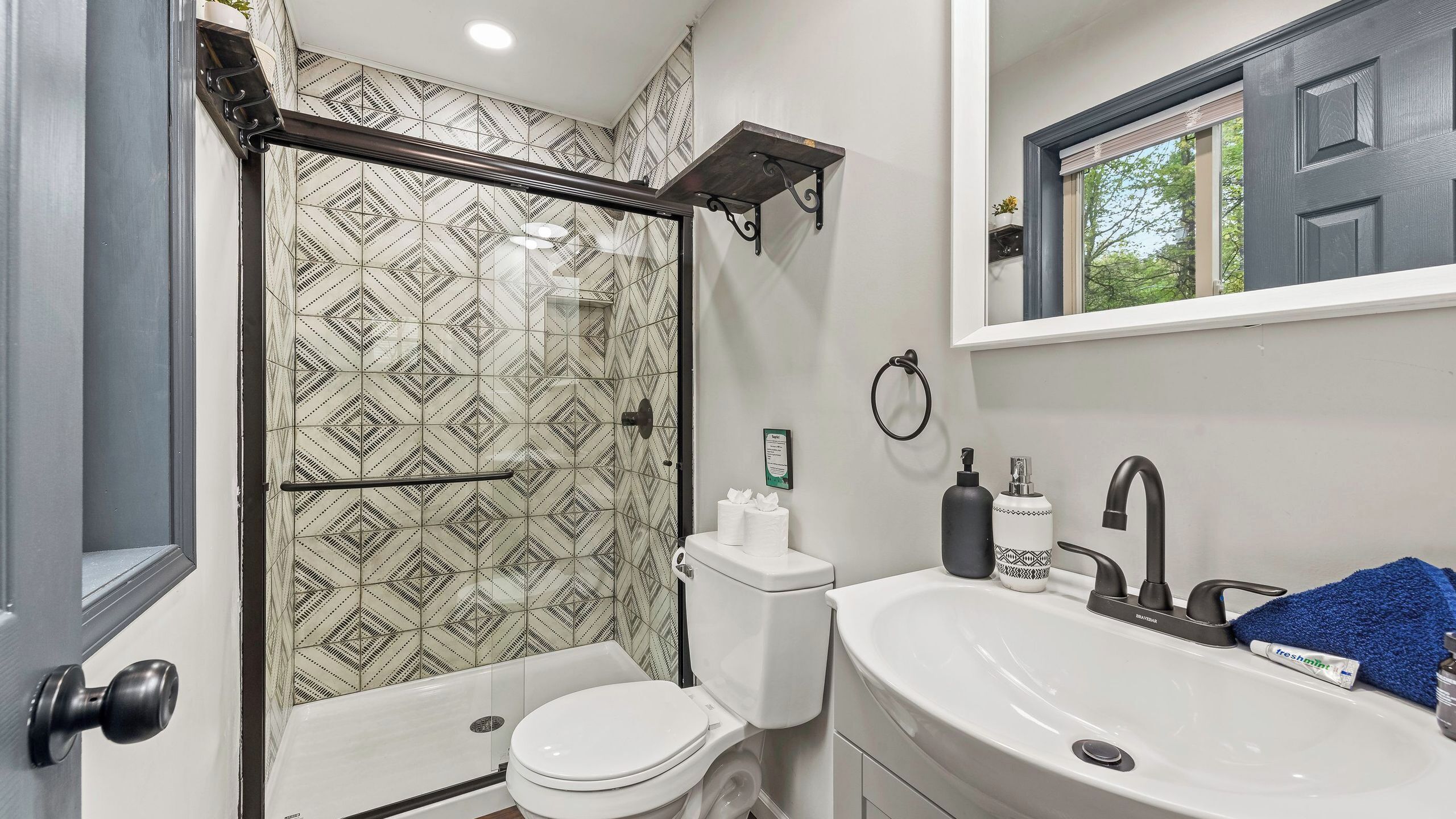 A bathroom with a shower, toilet, sink, and a mirror above the sink.
