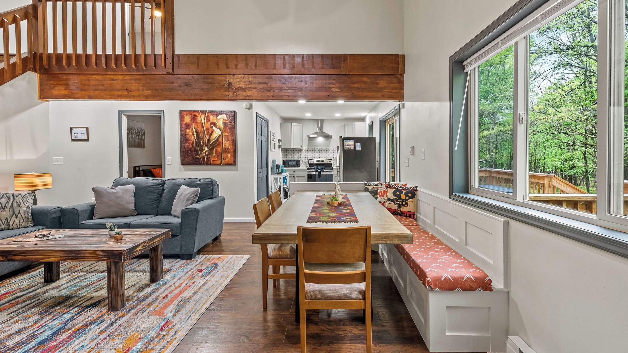 A spacious living room with a sofa, coffee table, and a dining area with a bench and chairs.