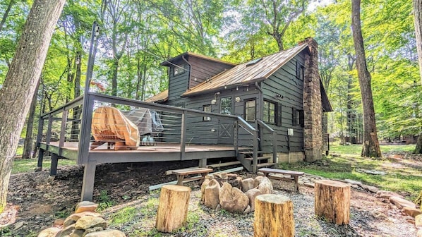 Un chalet rustique doté d’une terrasse, entouré d’arbres.