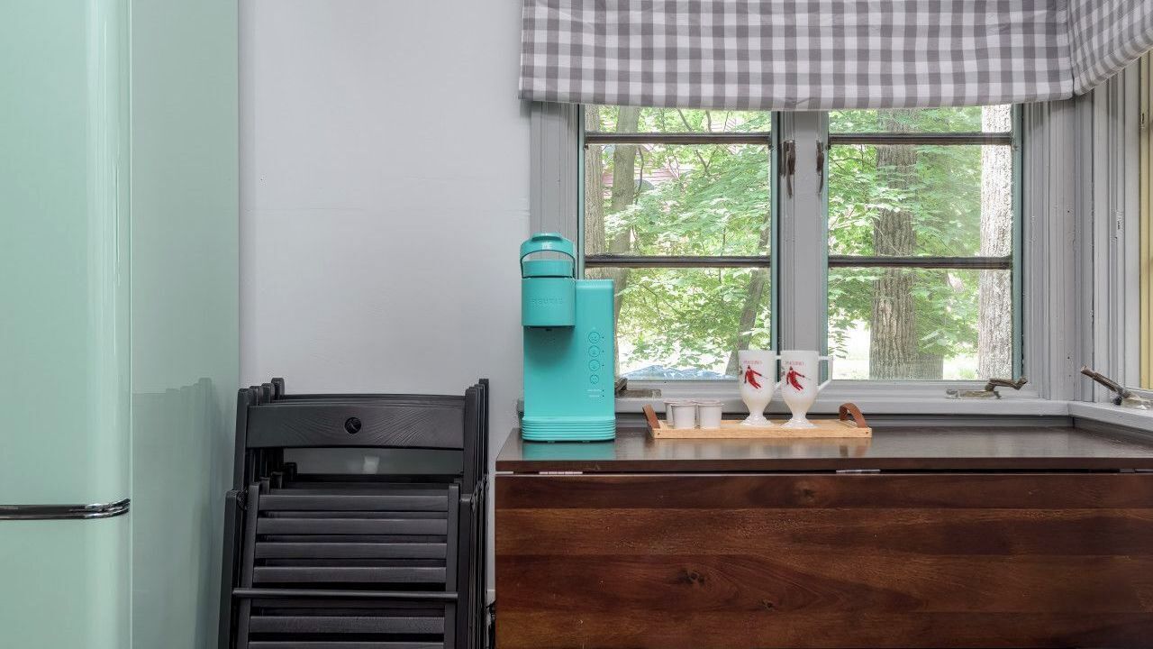 A kitchen with a window, a teal water dispenser, and a wooden countertop.