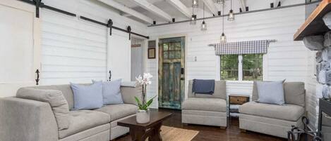 A spacious living room with wooden floors, a fireplace, and a large window.