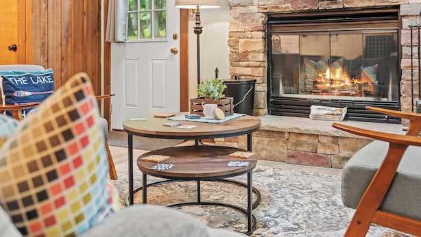 A cozy living room with a stone fireplace, a round coffee table, and comfortable seating.