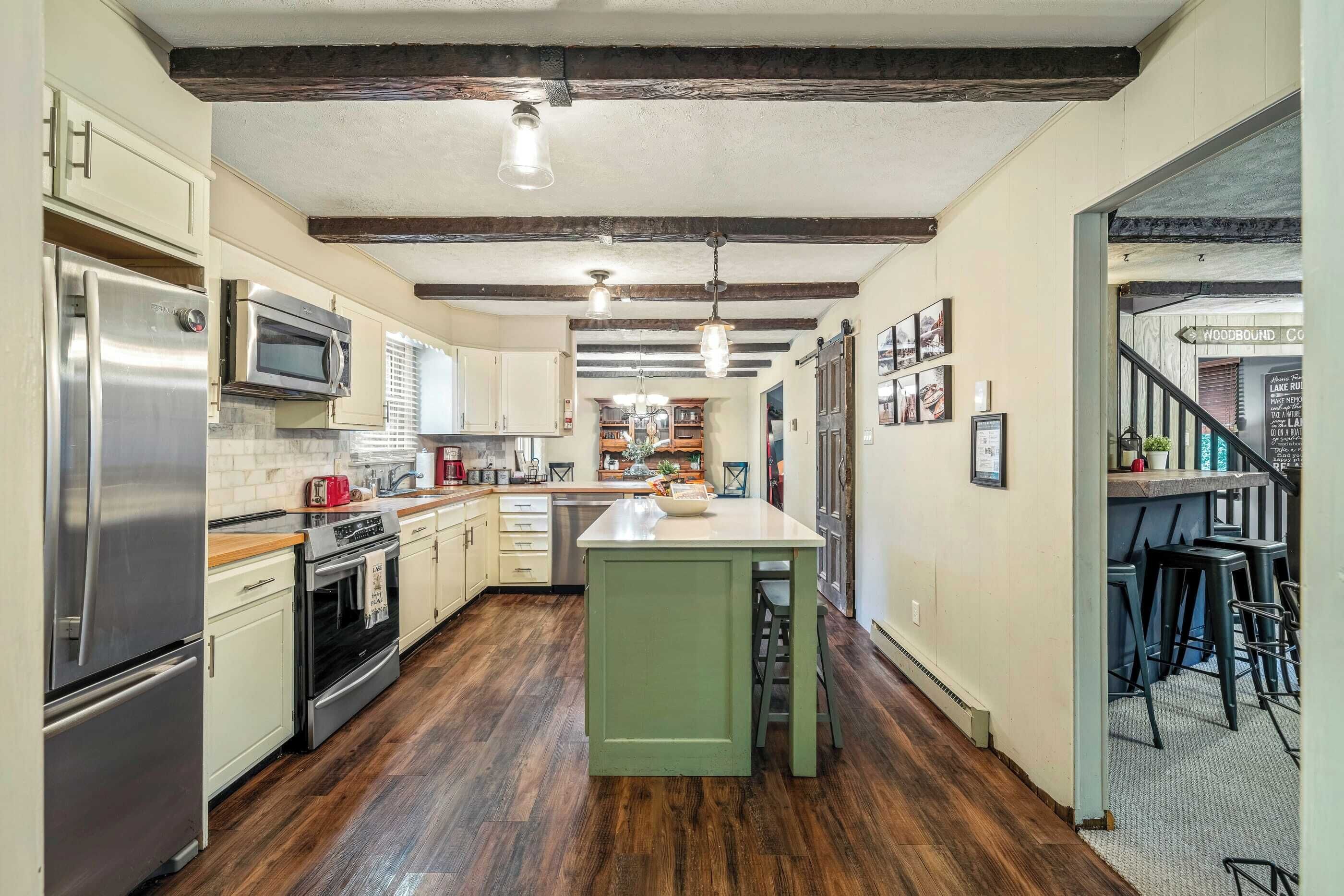 A kitchen with wooden floors, a central island, and a bar area with stools.