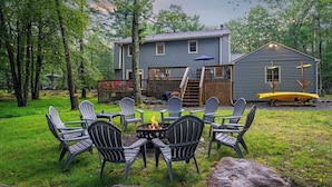 Ein Haus mit Terrasse, Sitzgelegenheiten im Freien und einer Feuerstelle.