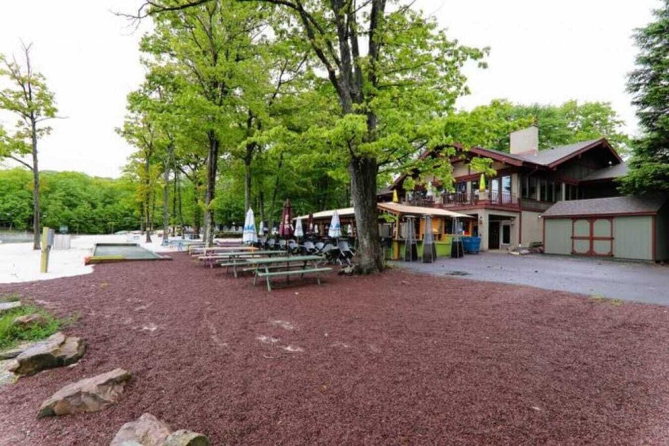 A lakeside lodge with outdoor seating and a building with a balcony.