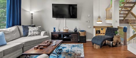 Una sala de estar con sofá, una mesa de centro y un televisor montado en la pared.
