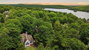 A house surrounded by dense forest with a lake in the background. - The Boulder Inn by Avantstay Indoor Hot Tub, Game Room, Outdoor Fire Pit (Lake Harmony)