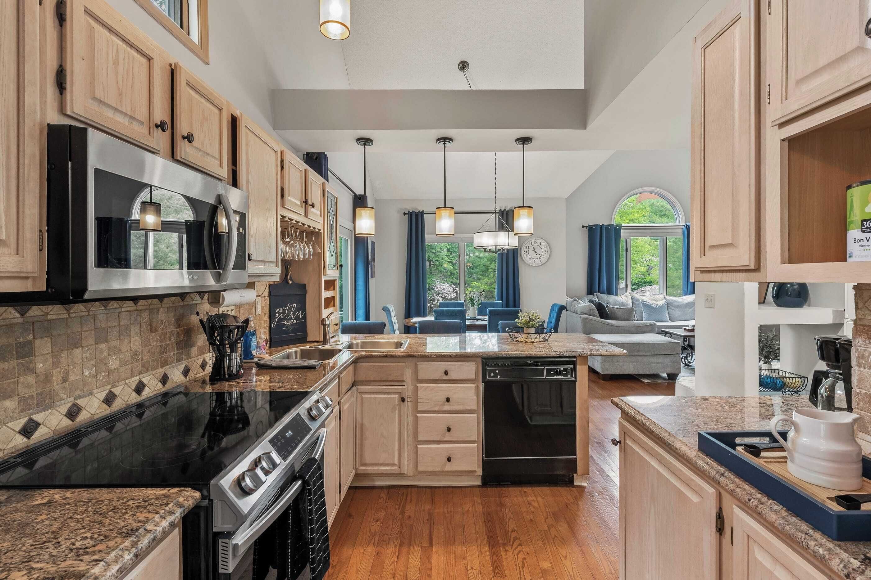 A modern kitchen with wooden cabinets, a stainless steel microwave, a black stove, and a dishwasher.