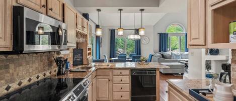 A modern kitchen with wooden cabinets, a stainless steel microwave, a black stove, and a dishwasher.