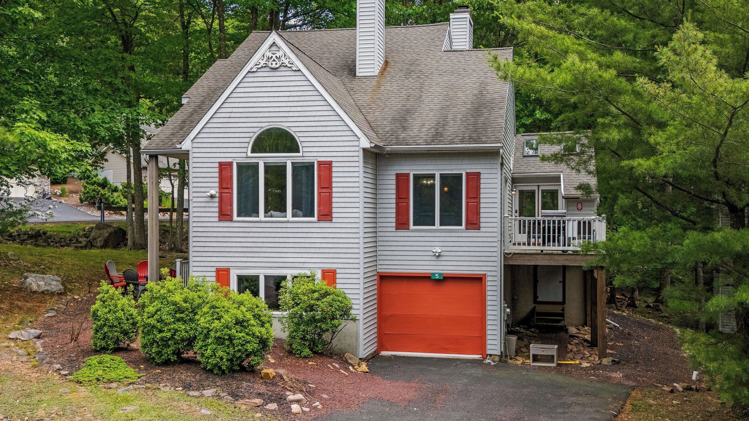 A two-story house with a red garage door, a balcony, and a chimney.