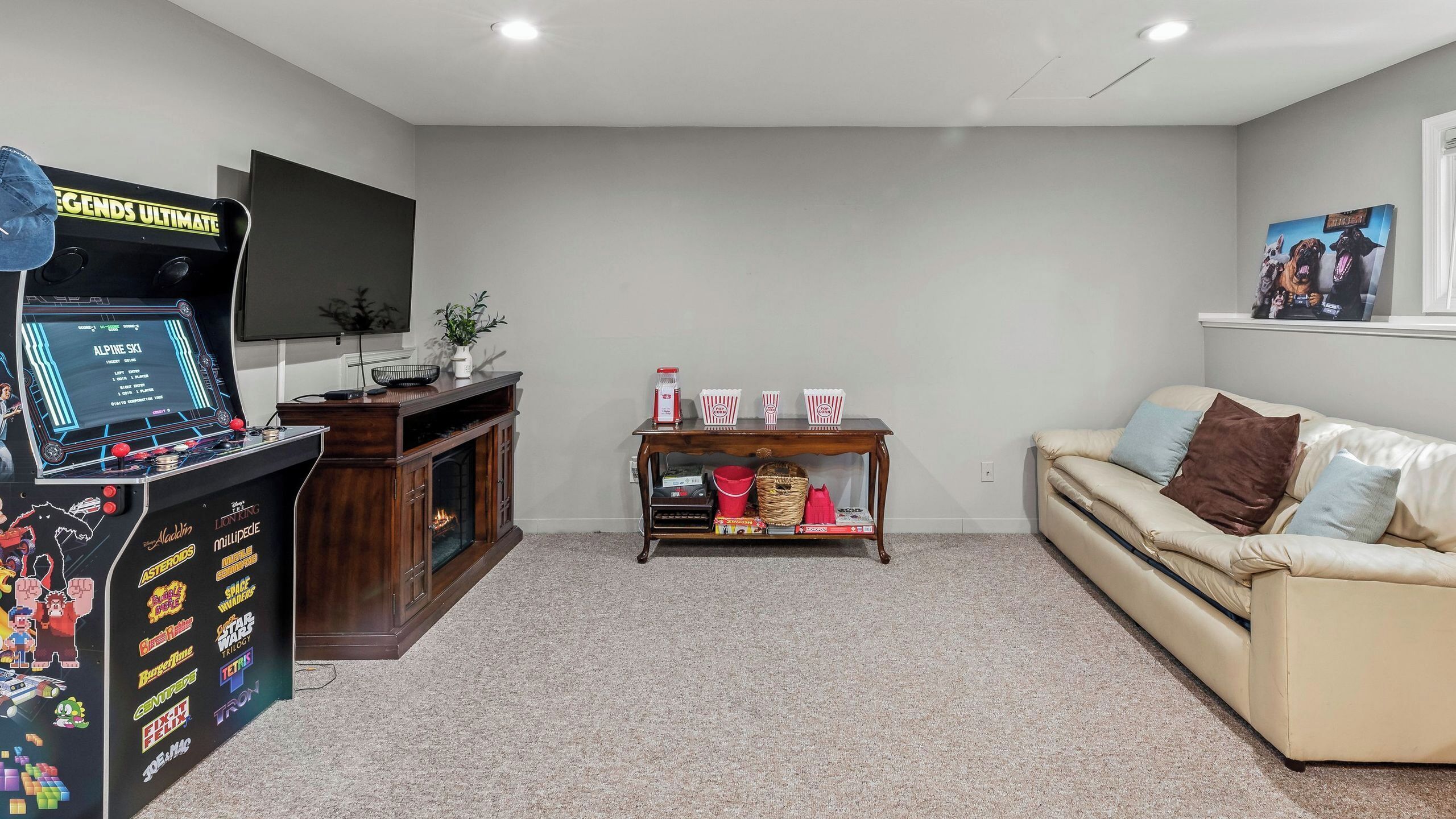 A living room with a gaming console, a fireplace, a sofa, and a small table with snacks.