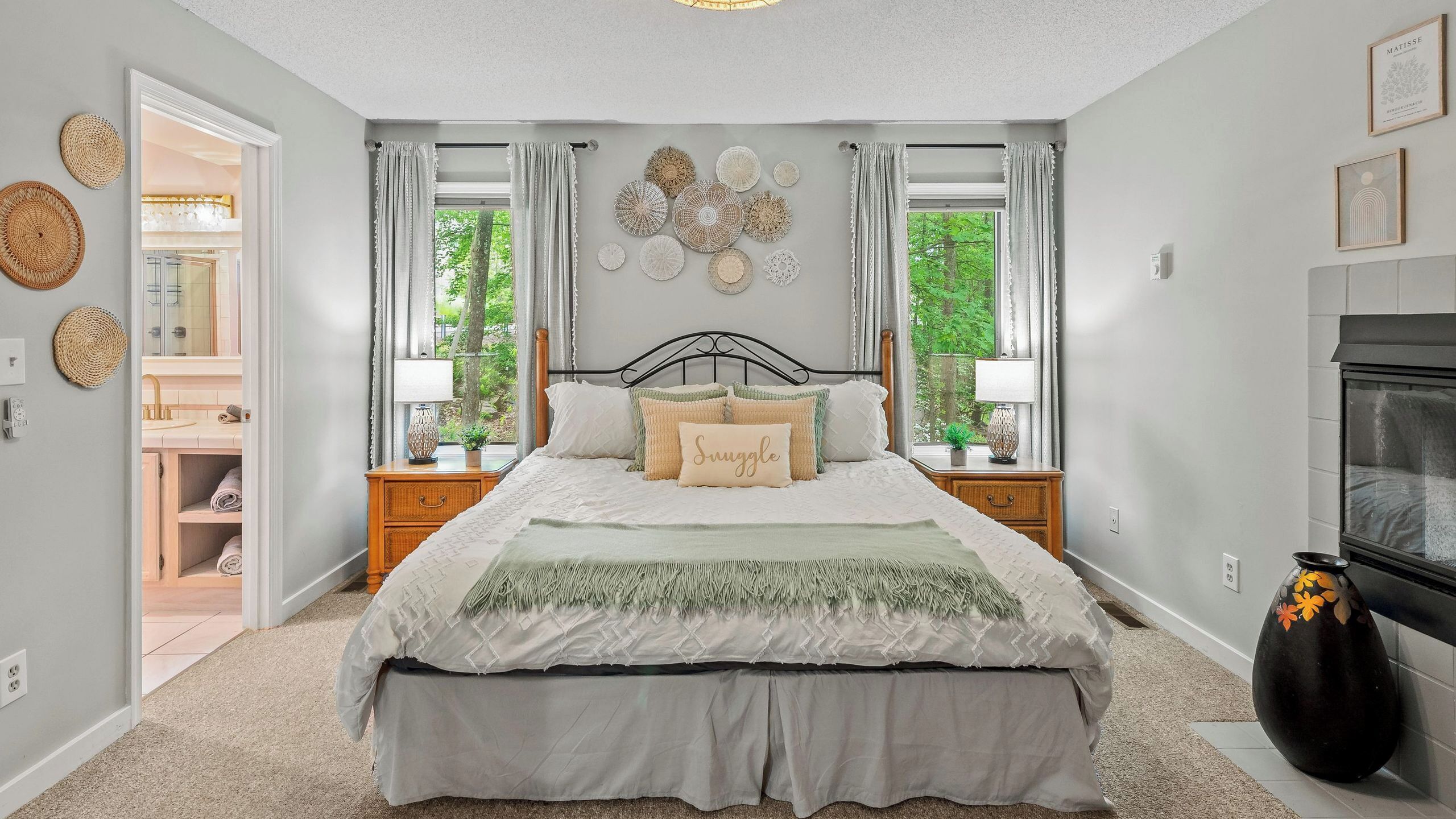 Une chambre à coucher comprenant un lit, deux tables de chevet, une commode, un miroir et une cheminée.