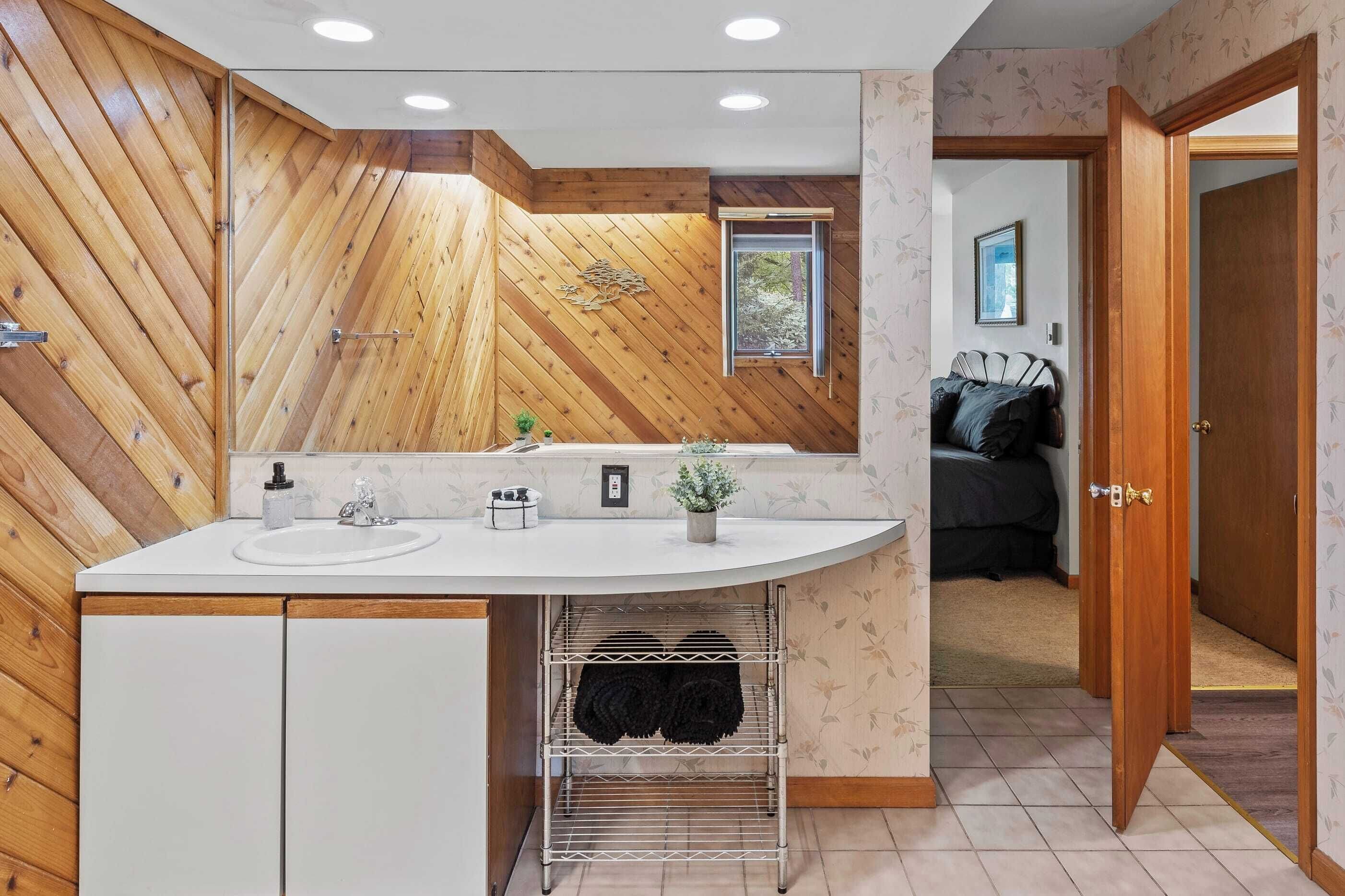 Une salle de bain moderne avec un mur d’accent en bois, un lavabo et un porte-serviettes.