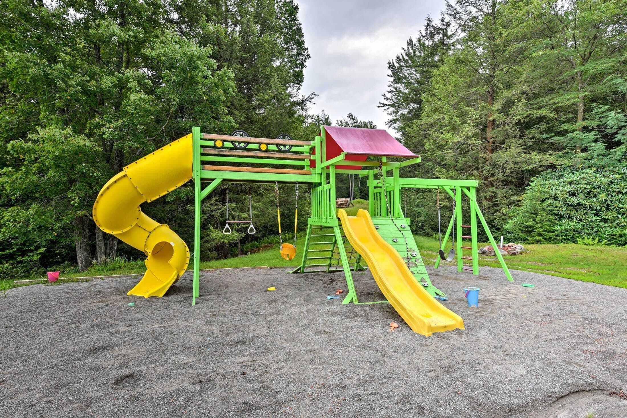 A playground with a yellow slide and a green climbing structure.