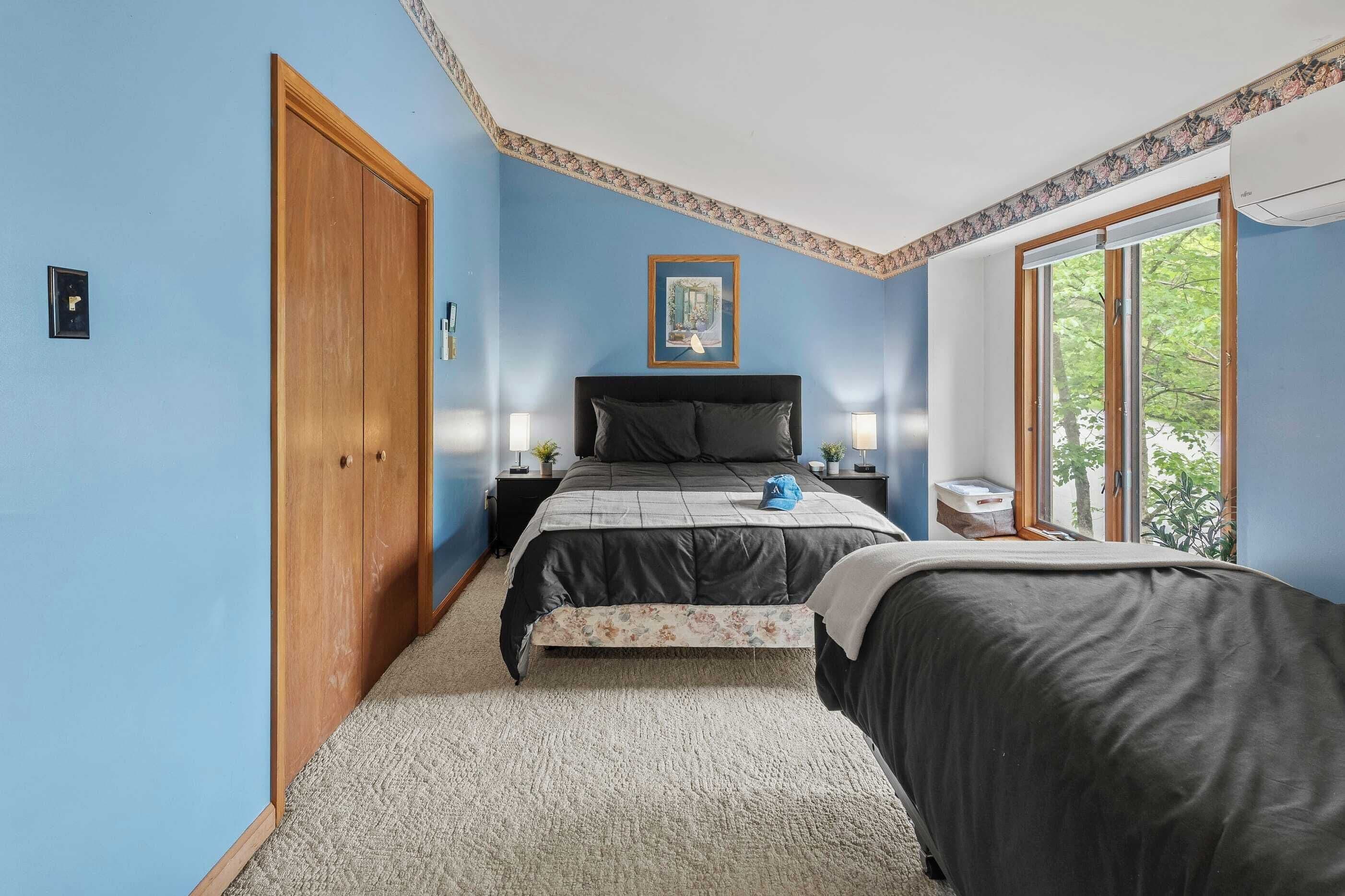A bedroom with a bed, a nightstand, a dresser, a window, and a door.