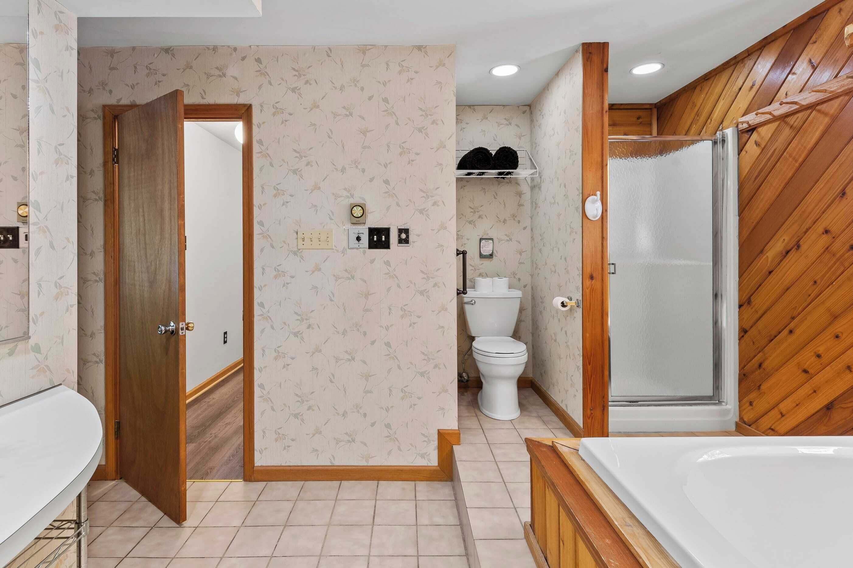 Un baño con tocador de madera, bañera, ducha y retrete.