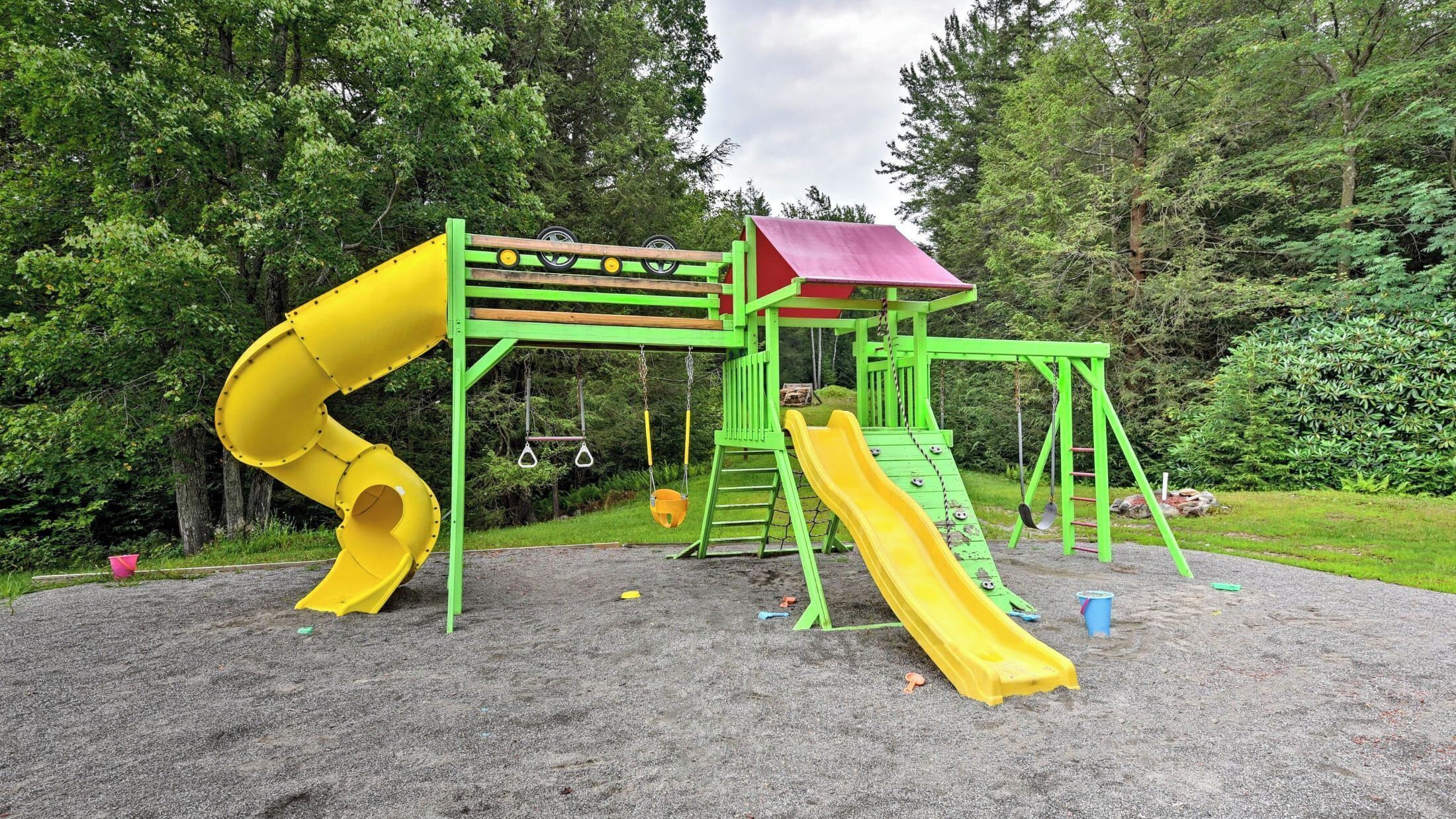 Un parque infantil con un tobogán amarillo y una estructura para escalar con techo rojo.