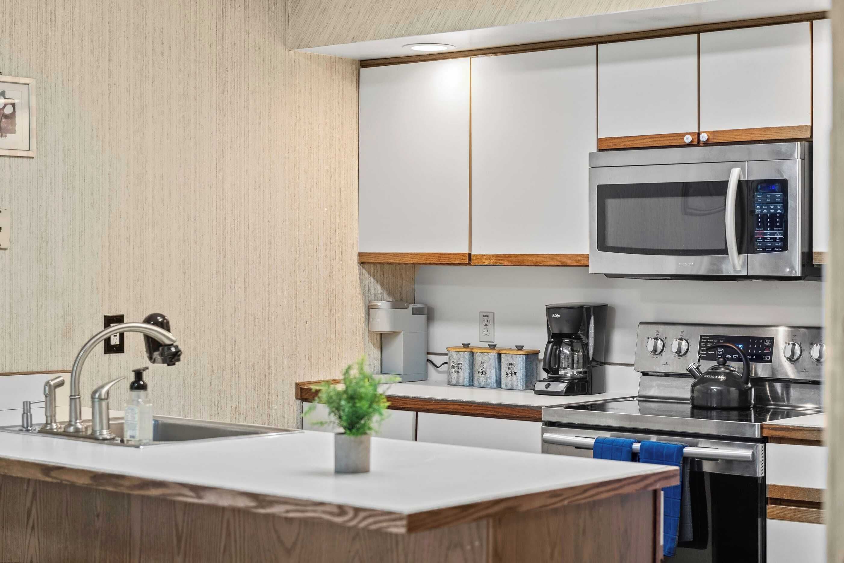Una cocina moderna con electrodomésticos de acero inoxidable, microondas integrado y cafetera.