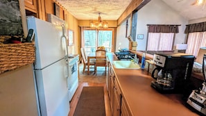 A kitchen with a refrigerator, stove, sink, and coffee maker.