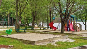 Un parque infantil con columpios, tobogán y arenero.